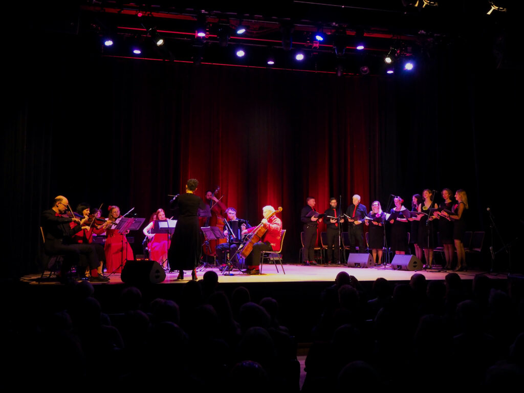 Na scenie gra i śpiewa chór i orkiestra Formacji Tango Para Todos. Dyryguje, odwrócona tyłem do publiczności, Agnieszka Kowalska. 